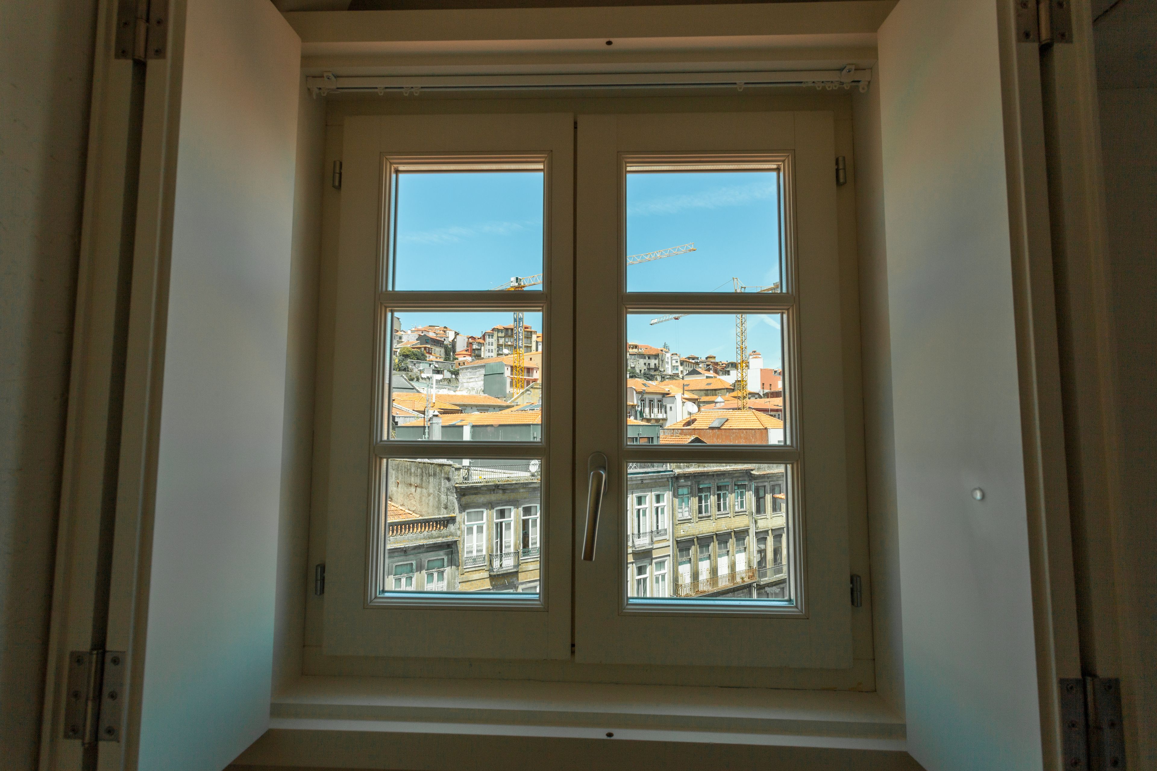 A window with a view of buildings and construction cranes.