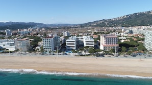 Un paisaje urbano costero con edificios modernos, una playa arenosa y aguas turquesas cristalinas.