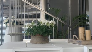 Una escalera espiral moderna con barandillas metálicas, un banco blanco y una planta en maceta con flores blancas.