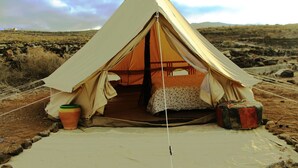 A tent with a bed inside, set up on a rocky ground with a clear sky in the background. - Twin Fin Surf Camp - Hostel (Adeje)