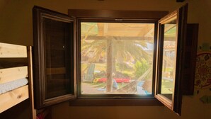 A room with a large window, a wooden bed, and a wall with a calendar. - Twin Fin Surf Camp - Hostel (Adeje)