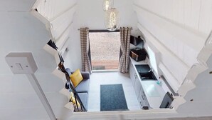 A compact, modern interior with a kitchenette, seating area, and a view of the outdoors. - Acdc Glamping, Campervan , Caravan and Tent Resort (Fraserburgh)