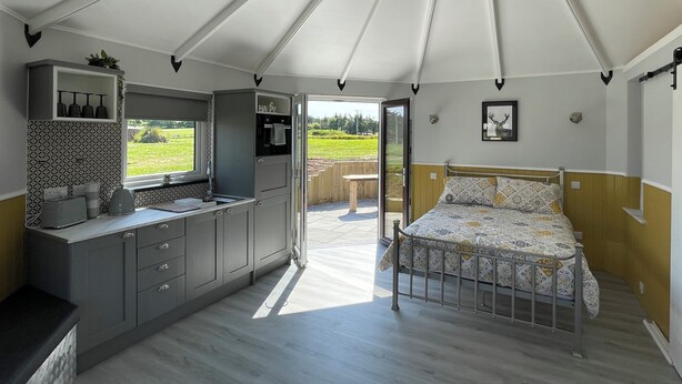 A tented accommodation with a kitchenette, a bed, and a view of the outdoors. - Acdc Glamping, Campervan , Caravan and Tent Resort (Fraserburgh)