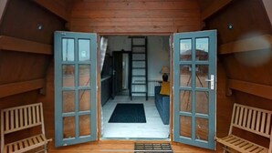 A wooden cabin with a loft bedroom, a staircase, and a living area with a sofa and a lamp. - Acdc Glamping, Campervan , Caravan and Tent Resort (Fraserburgh)