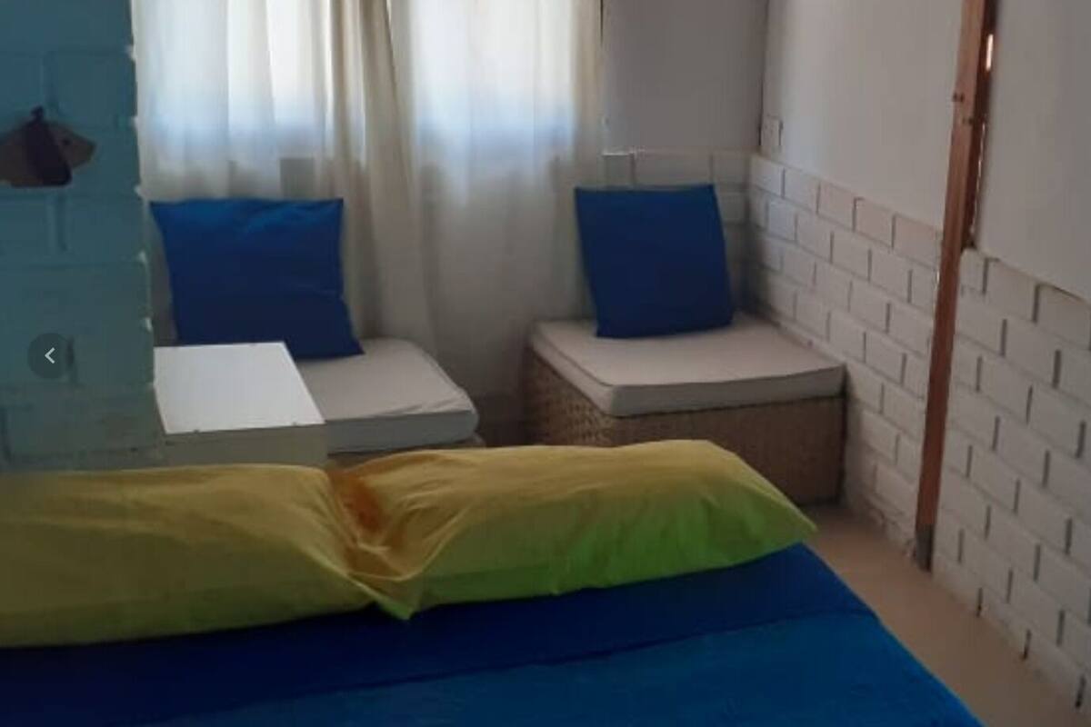 A bedroom with a bed, a small bedside table, a bench, and a wardrobe.
