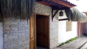 Un edificio de piedra con puerta de madera y techo de paja.