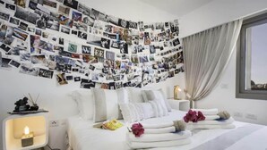 Ein Hotelzimmer mit einem Bett, einem Nachttisch mit Lampe und einer Wand voller Fotos.
