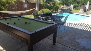 A pool table with billiard balls, a pool table, and a pool. - 4 Bedroom With Landscaped Private Pool & Outdoor Pool Table ~MONTHLY DISCOUNT~ (McKinney)