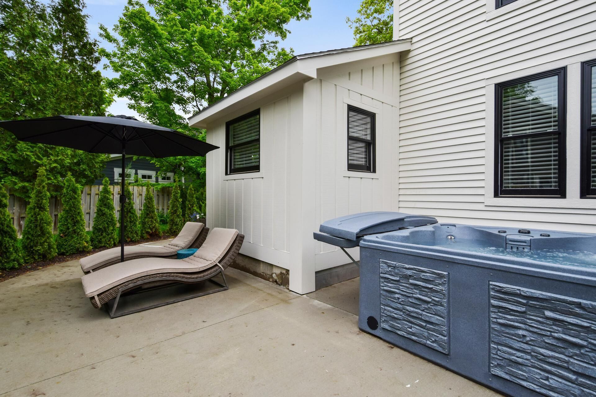 A patio with two lounge chairs and a hot tub.