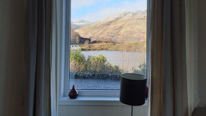 Janela com vista para um lago e montanhas.