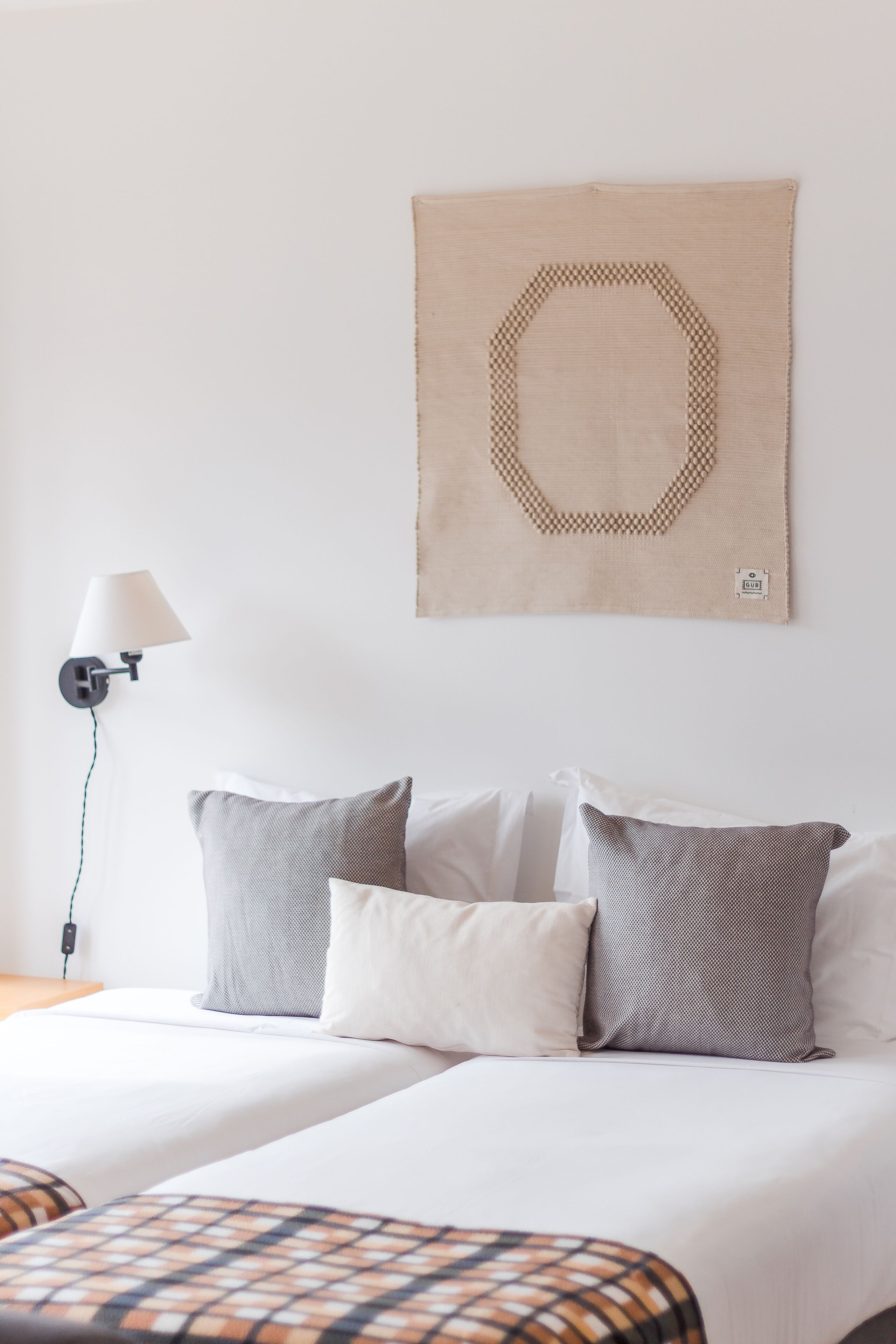 Ein Hotelzimmer mit einem Bett, zwei Kissen, einer Wandlampe und einem Wandbild.