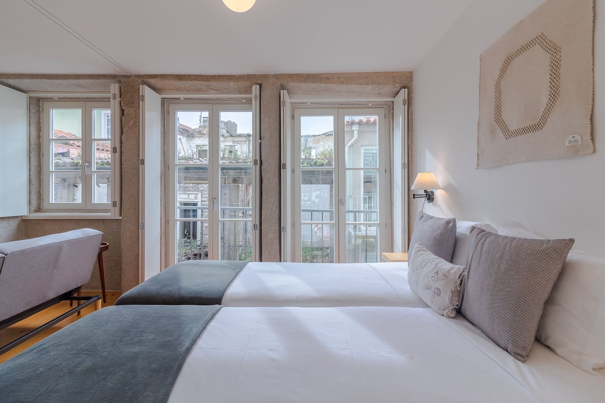 Un dormitorio con cama, mesita de noche, lámpara y vistas amplias a través de grandes ventanales.