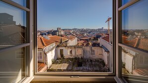 A view from a window overlooking a cityscape with historical buildings and a construction crane.