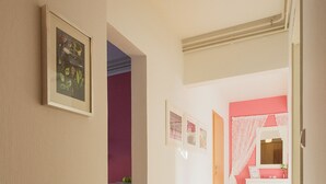 Ein Korridor mit Holzboden, einem weißen Schminktisch und einer rosa Wand.