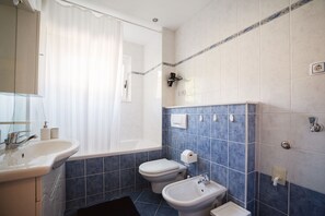Ein Badezimmer mit Waschbecken, Bidet, Toilette und Badewanne.