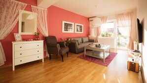 Ein Wohnzimmer mit Sofa, Sessel und Couchtisch, einem weißen Kommoden und einem Flachbildfernseher.