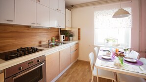 Eine moderne Küche mit Holzausstattung, einem Gasherd und einem Essbereich mit Tisch für zwei Personen.