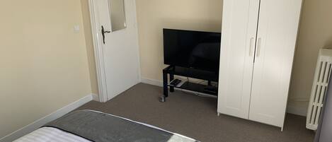 A bedroom with a bed, a TV, a wardrobe, and a radiator.