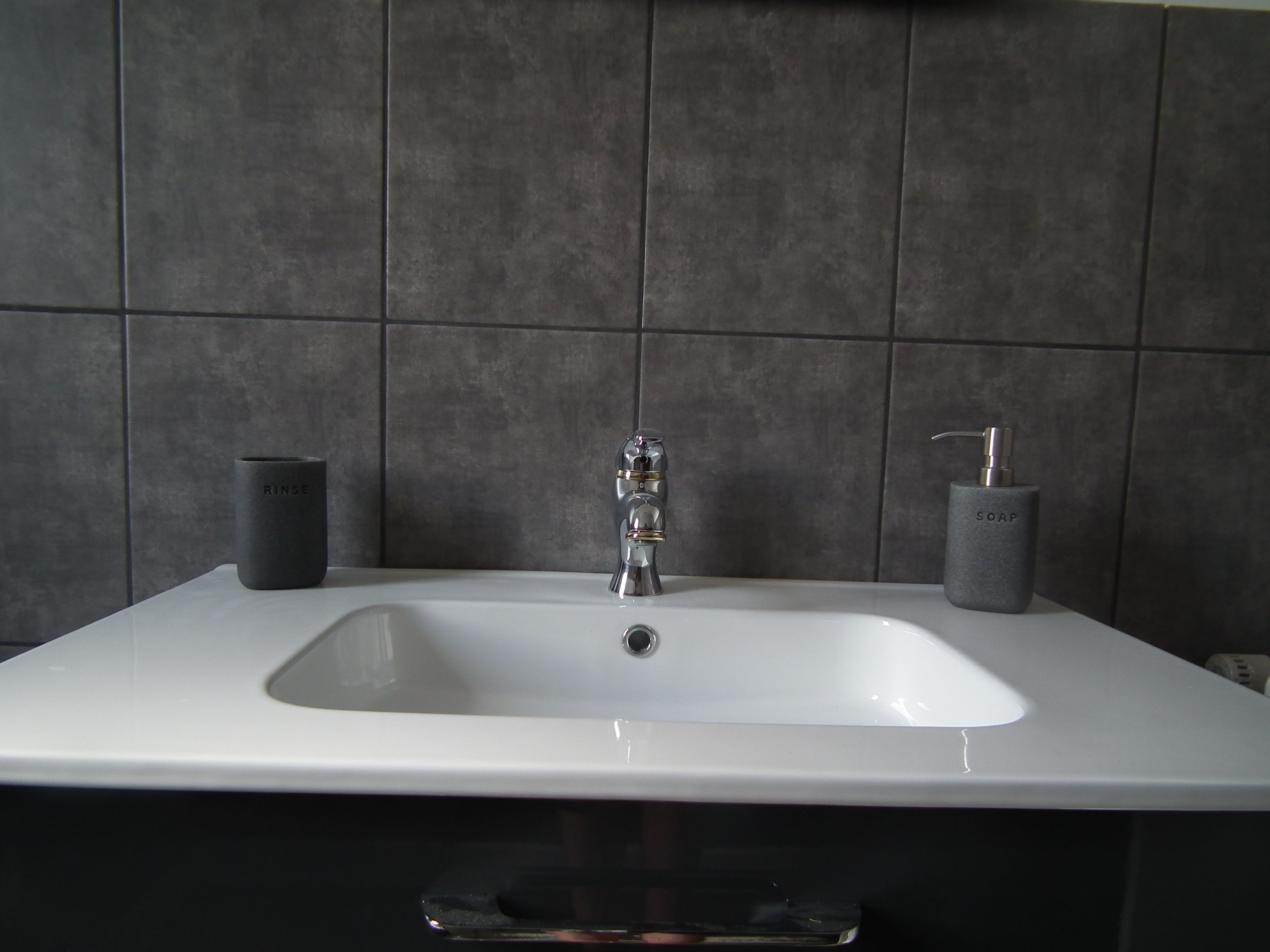 A bathroom sink with a modern faucet, two soap dispensers, and a glass soap dish.