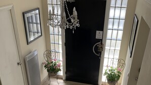 A hallway with a black door, a chandelier, and two potted plants. - No 6 Bed & Breakfast (Landivy)