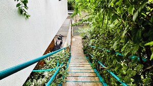 A narrow staircase with blue railings, surrounded by lush greenery and a white building. - Palmare House (San Andrés)