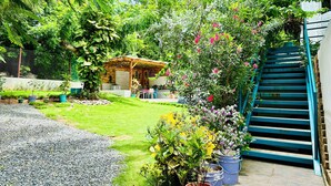 A garden with a pergola, a small table, and chairs, surrounded by potted plants and a staircase. - Palmare House (San Andrés)