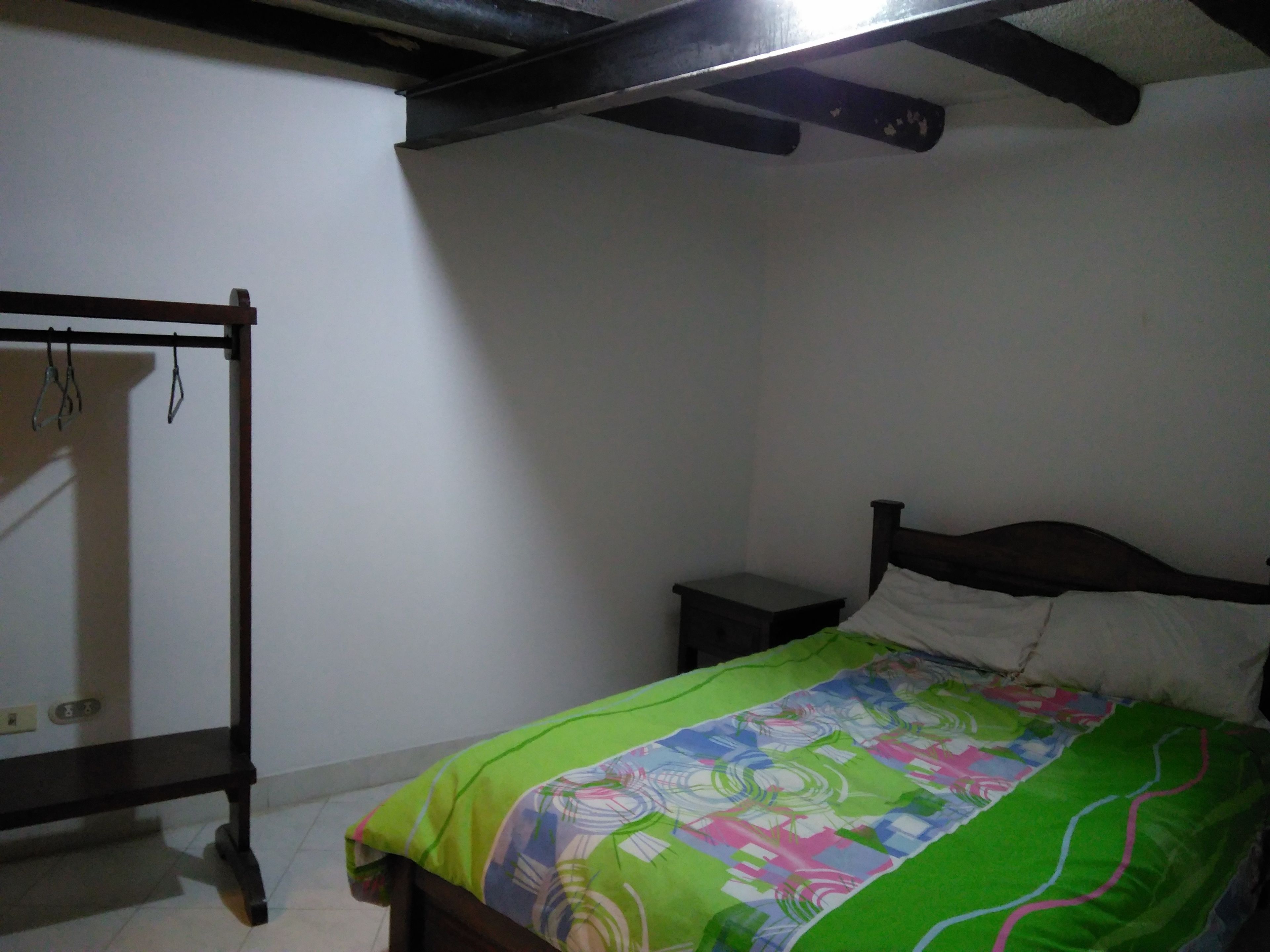 A bedroom with a wooden bed, a nightstand, and a wooden wardrobe.