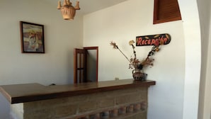 A reception desk with a wooden top and a brick base, a sign reading "Reception", and a vase with dried flowers on the wall. - Hotel Rural Posada de los Santos (Ráquira)