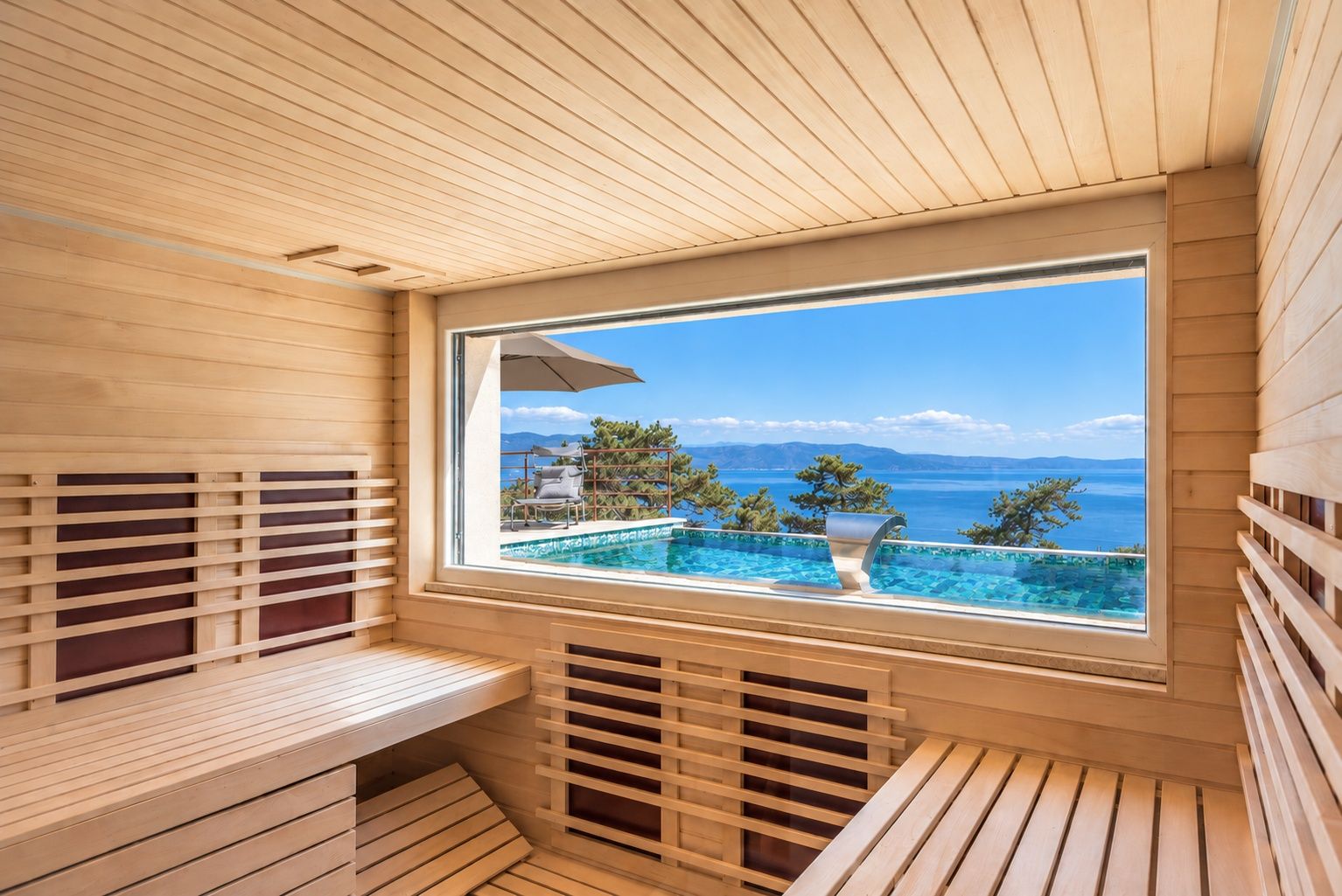 Ein Saunaraum mit großem Fenster mit Blick auf ein Schwimmbad und eine schöne Aussicht.