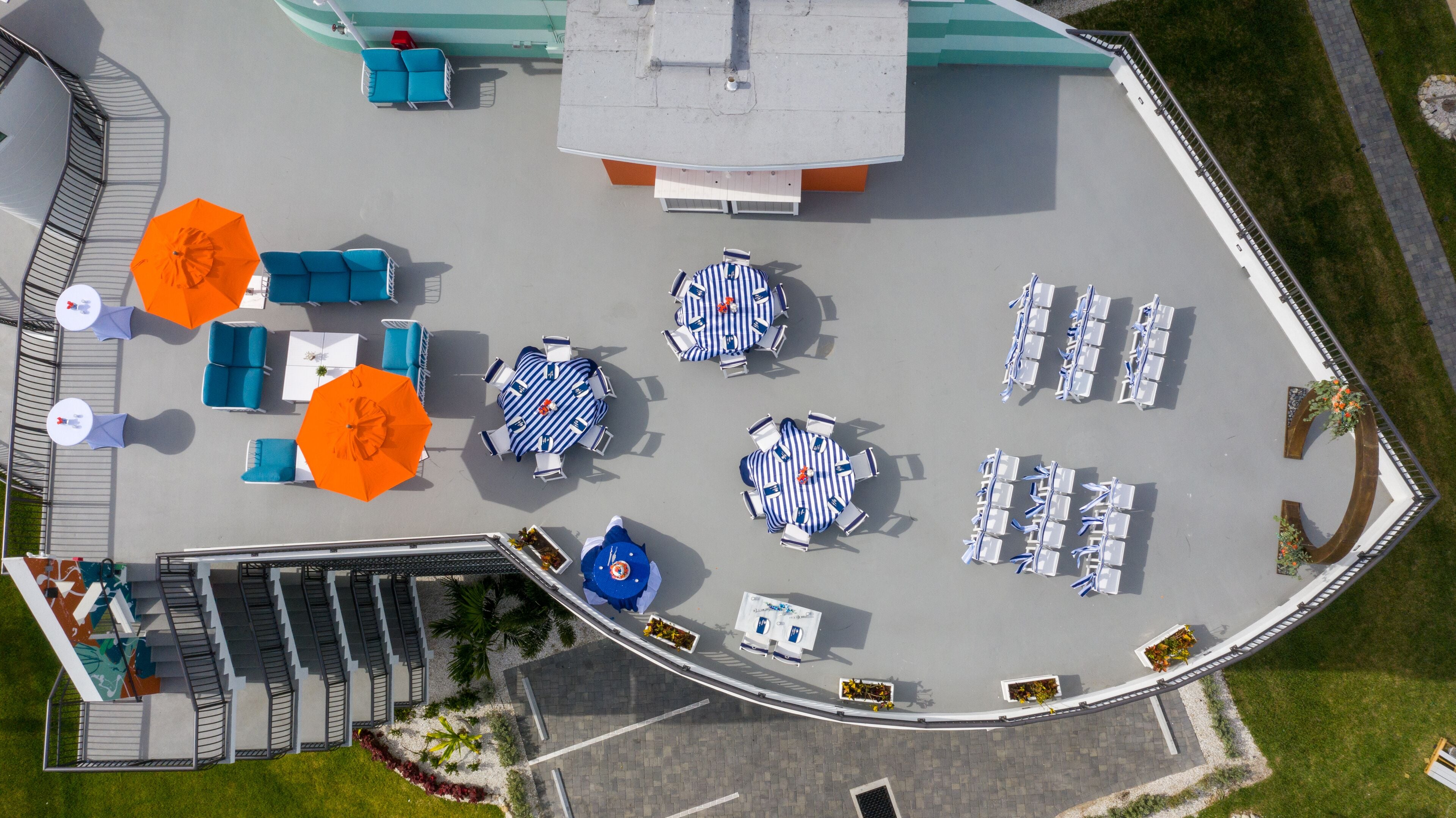 Luchtbeeld van een hotelterras met buitenmeubilair, een trap en een zwembad.