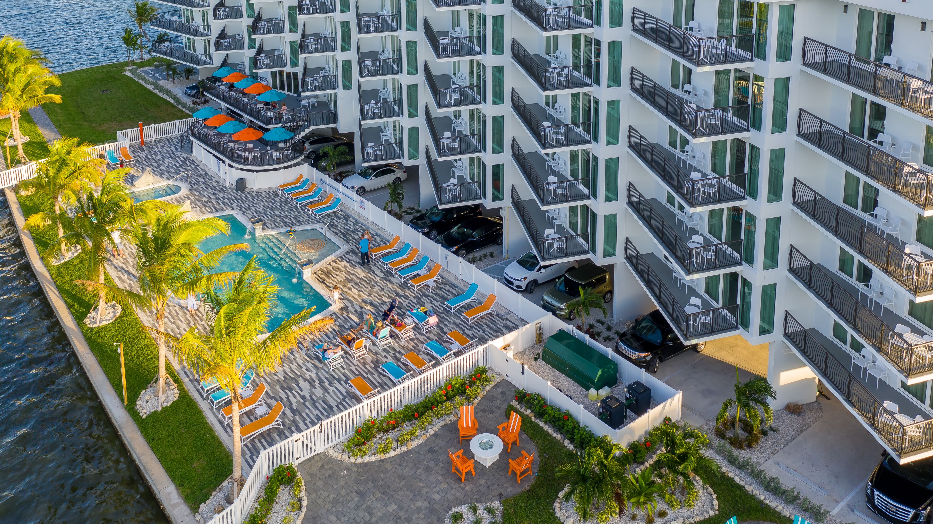 A modern hotel with multiple balconies, a swimming pool, and outdoor seating areas.