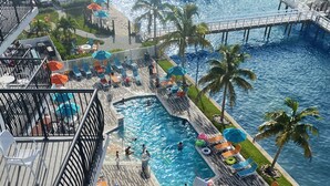 A rooftop pool area with multiple pools, lounge chairs, and umbrellas. - FUSION Resort Waterfront Suites (Treasure Island)