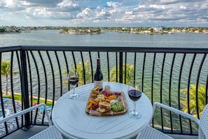 Enjoy a meal on the balcony overlooking the water with a view of the distant shoreline and surrounding greenery.