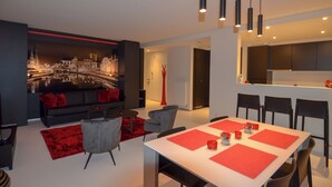 A modern living room with a black sofa, red cushions, and a red rug. There is a dining area with a white table and red placemats. - Lord of Ghent Luxurious apartment in historical center of Ghent (Gent)