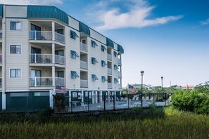 A multi-story hotel with balconies, a swimming pool, and American flags.
