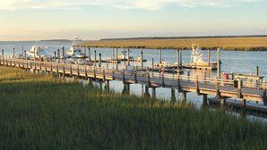 A wooden pier extending into calm water with boats docked at the end.