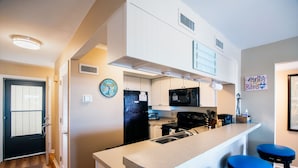 A modern kitchen with a central island, built-in appliances, and a bar stool area.