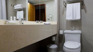 Un baño moderno con un espejo grande, un inodoro y un lavamanos.