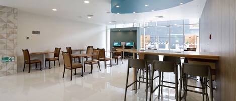 A modern dining area with tables and chairs, a counter, and a large window with a view.
