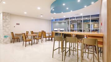 Un comedor moderno con mesas y sillas, un muro de cristal con vistas y una pared decorada en azul.