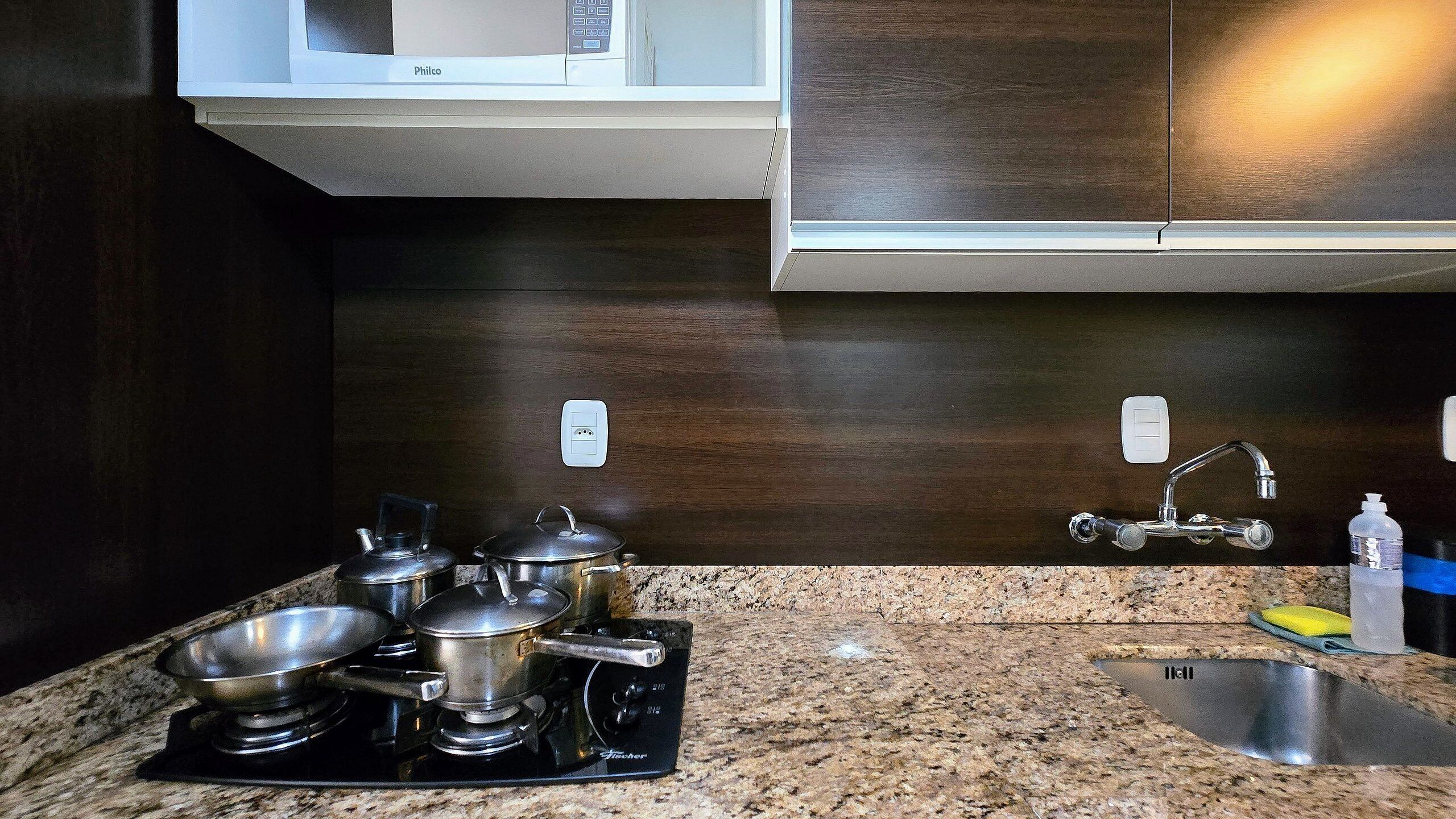 A kitchen with granite countertops, stainless steel appliances, a sink, and a microwave.