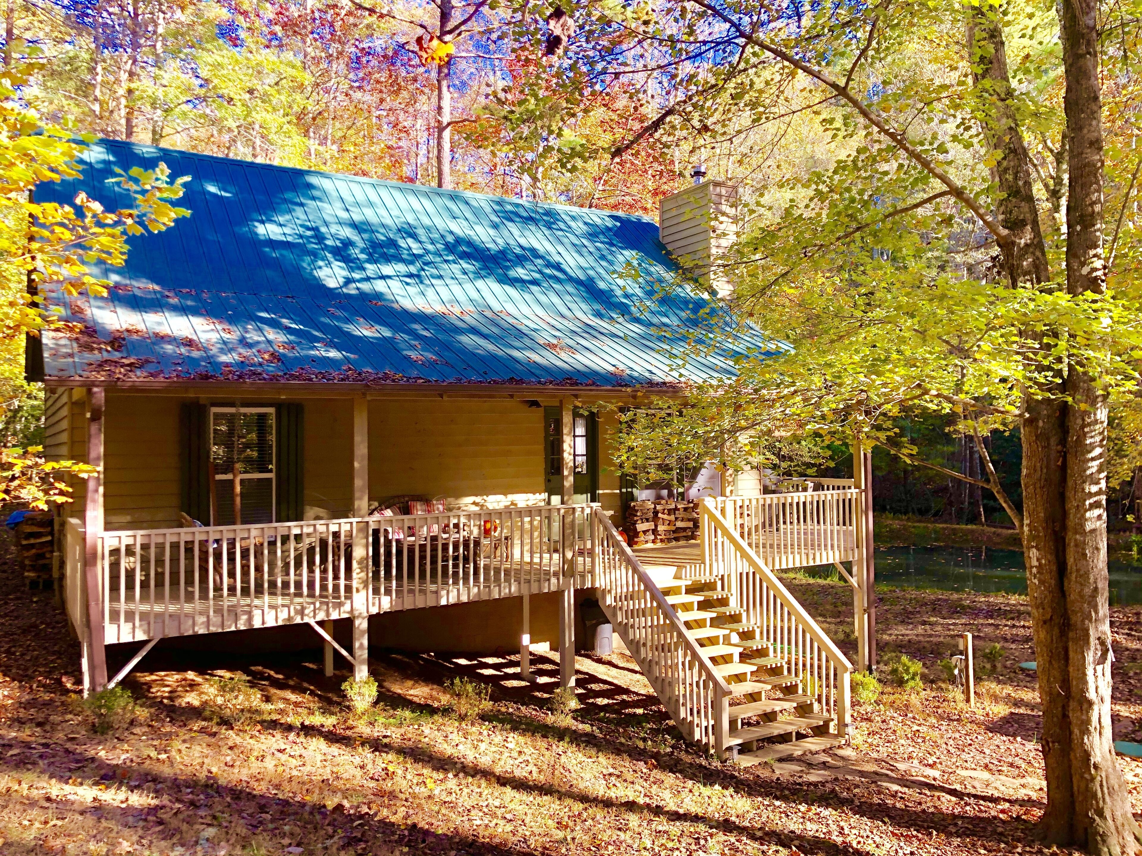 Une cabane rustique avec un toit bleu, une véranda en bois et un escalier menant à l’entrée.