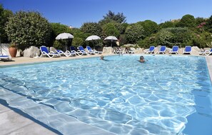 Ein Schwimmbad mit klarem Wasser, umgeben von blauen Liegestühlen und Sonnenschirmen.