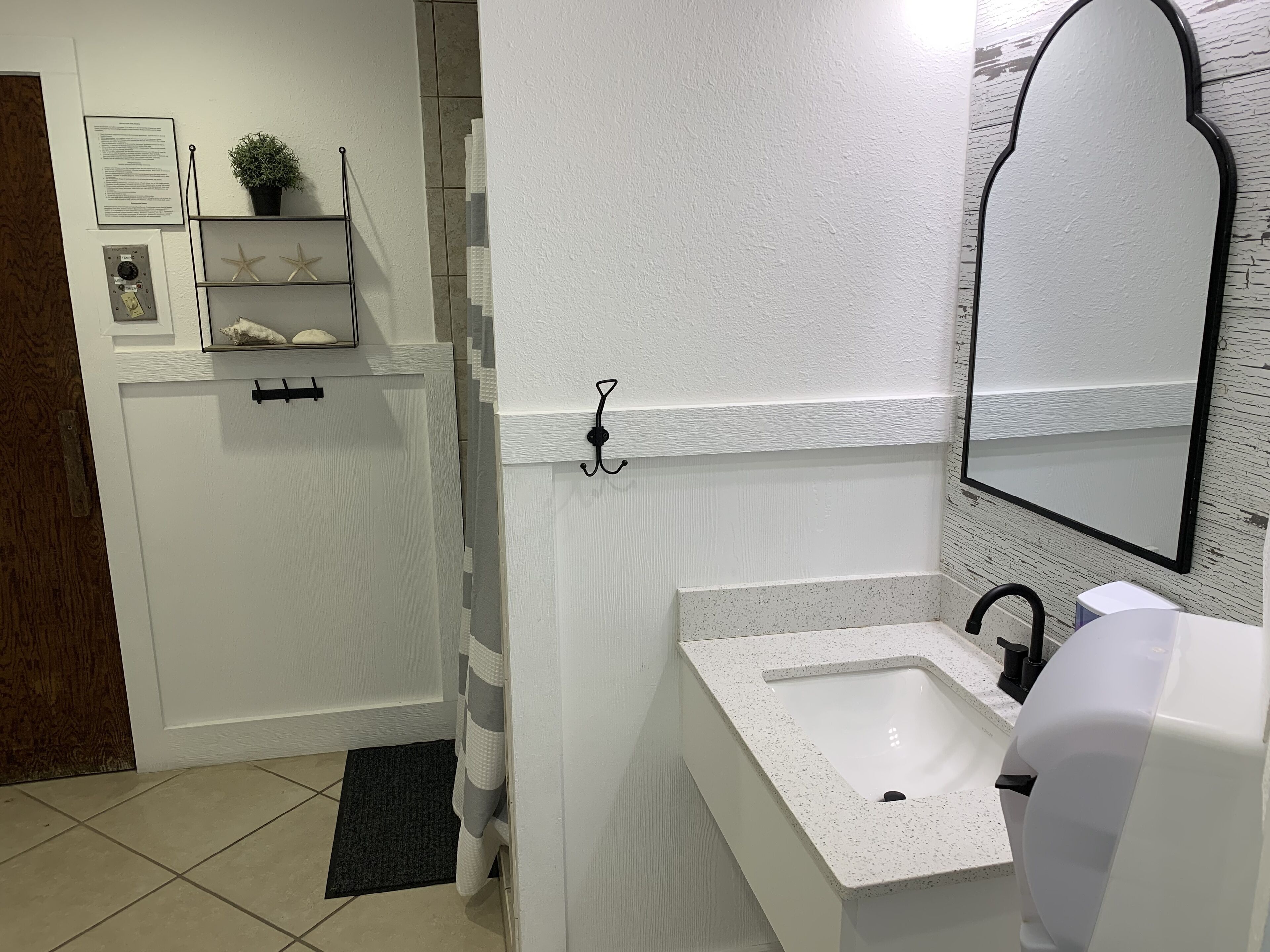 A bathroom with a white sink, a mirror, and a shower area.