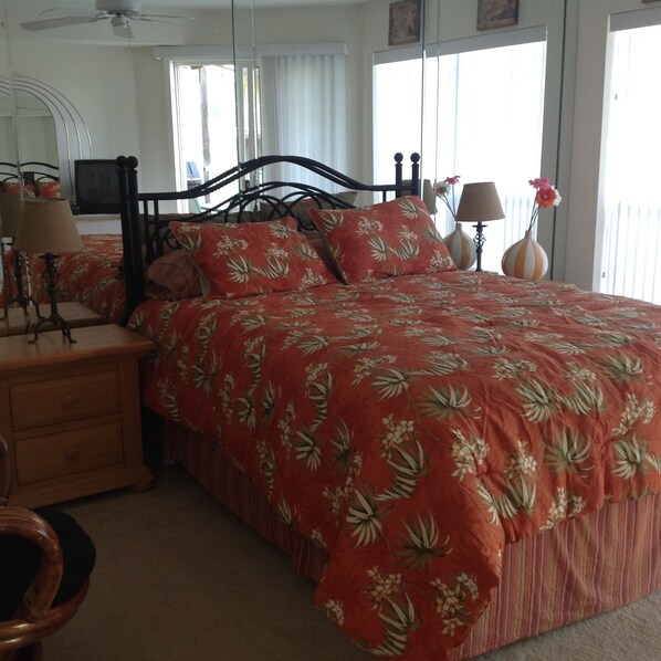 A bedroom with a bed, nightstands, a mirror, and a window.