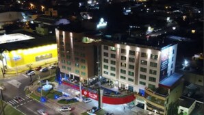 Un hôtel à plusieurs étages doté d’une cour intérieure, d’un parking et d’une grande enseigne lumineuse sur la façade.
