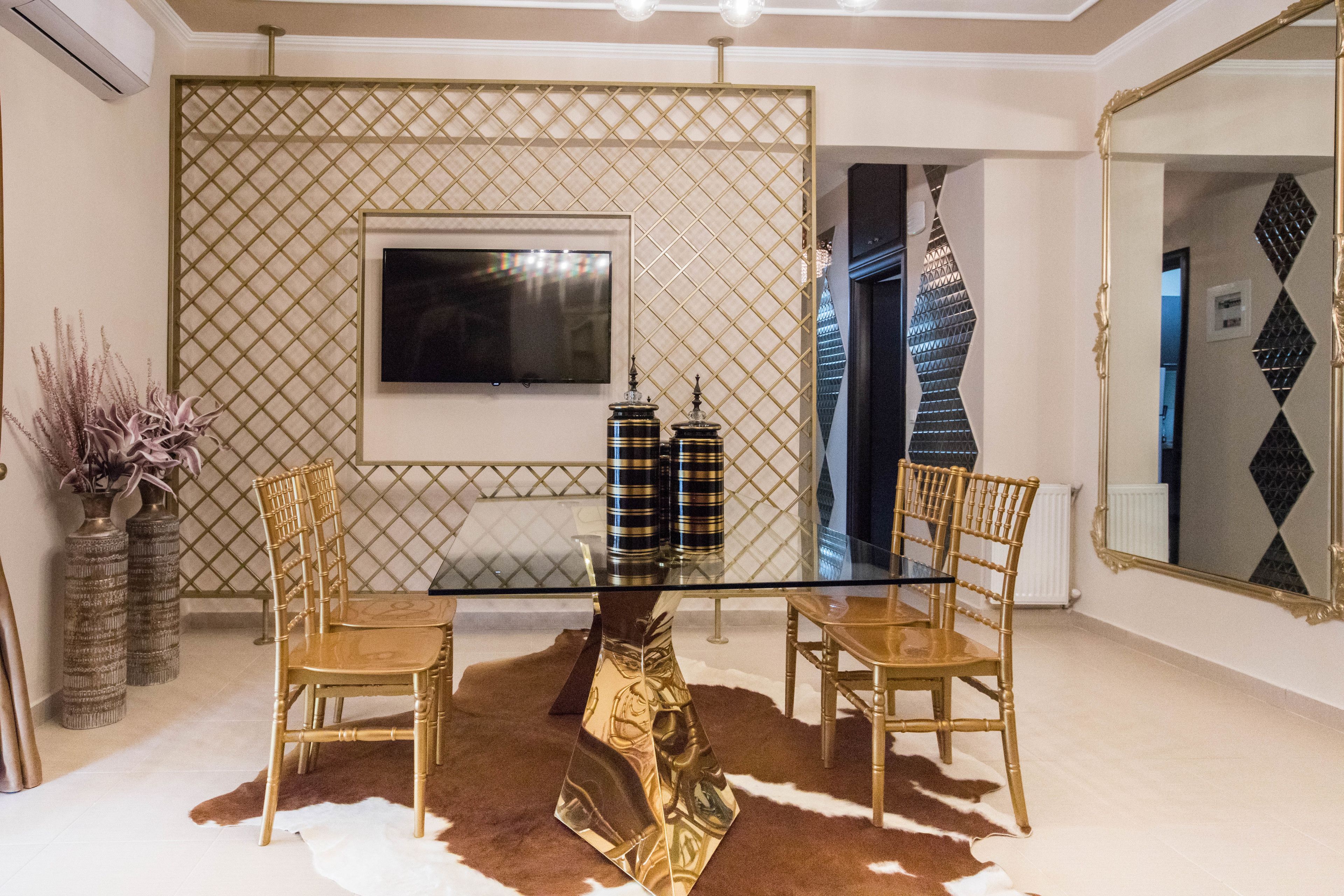 Un comedor con una mesa de vidrio, dos sillas, un jarrón decorativo y un televisor en la pared.