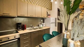 Een moderne keuken met houten kastjes, een roestvrijstalen oven, een spoelbak en een koffiezetapparaat. Op het aanrecht staan twee stoelen en een vaas met bloemen.