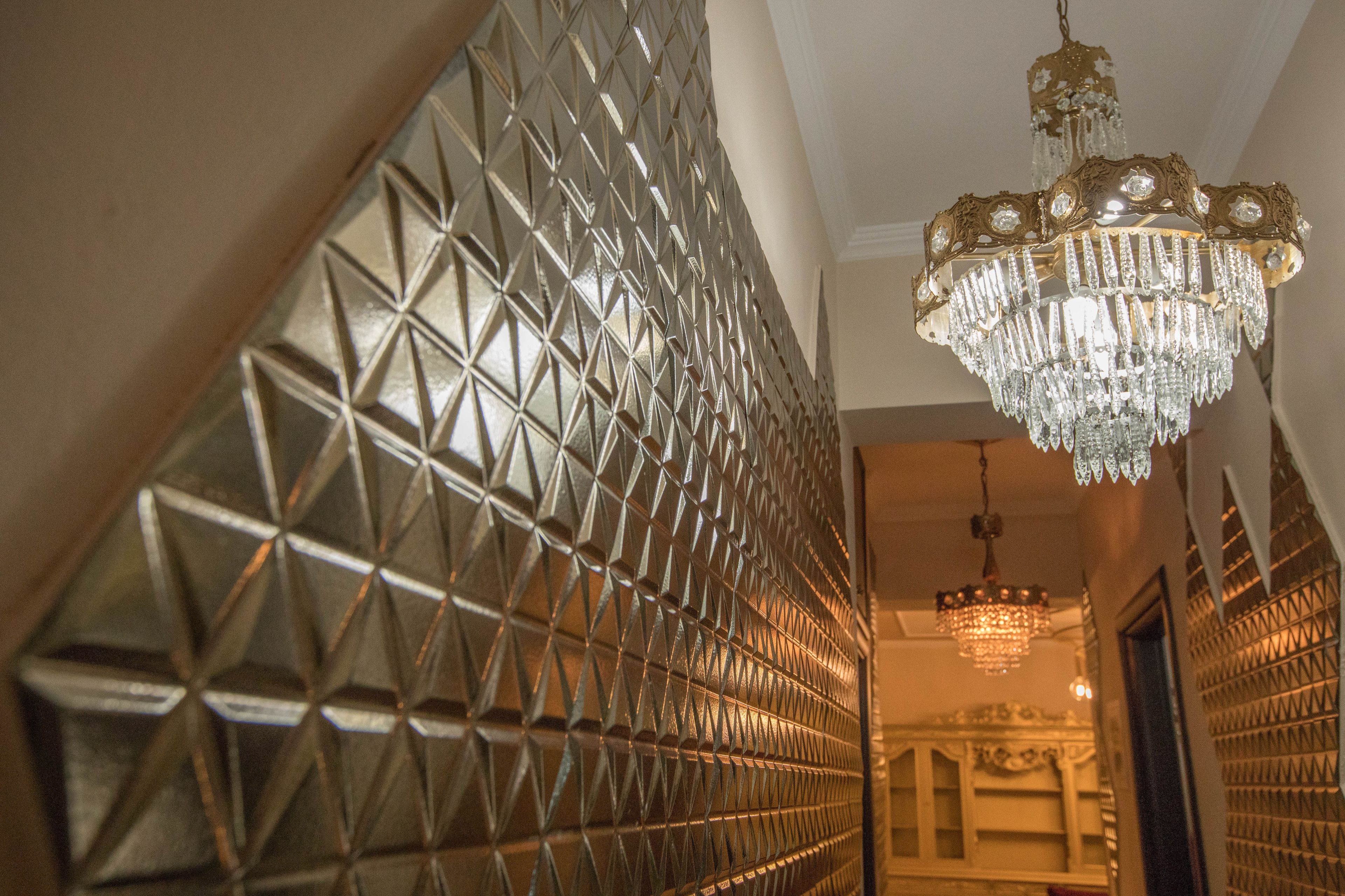 A hallway with a geometric patterned wall and a chandelier.