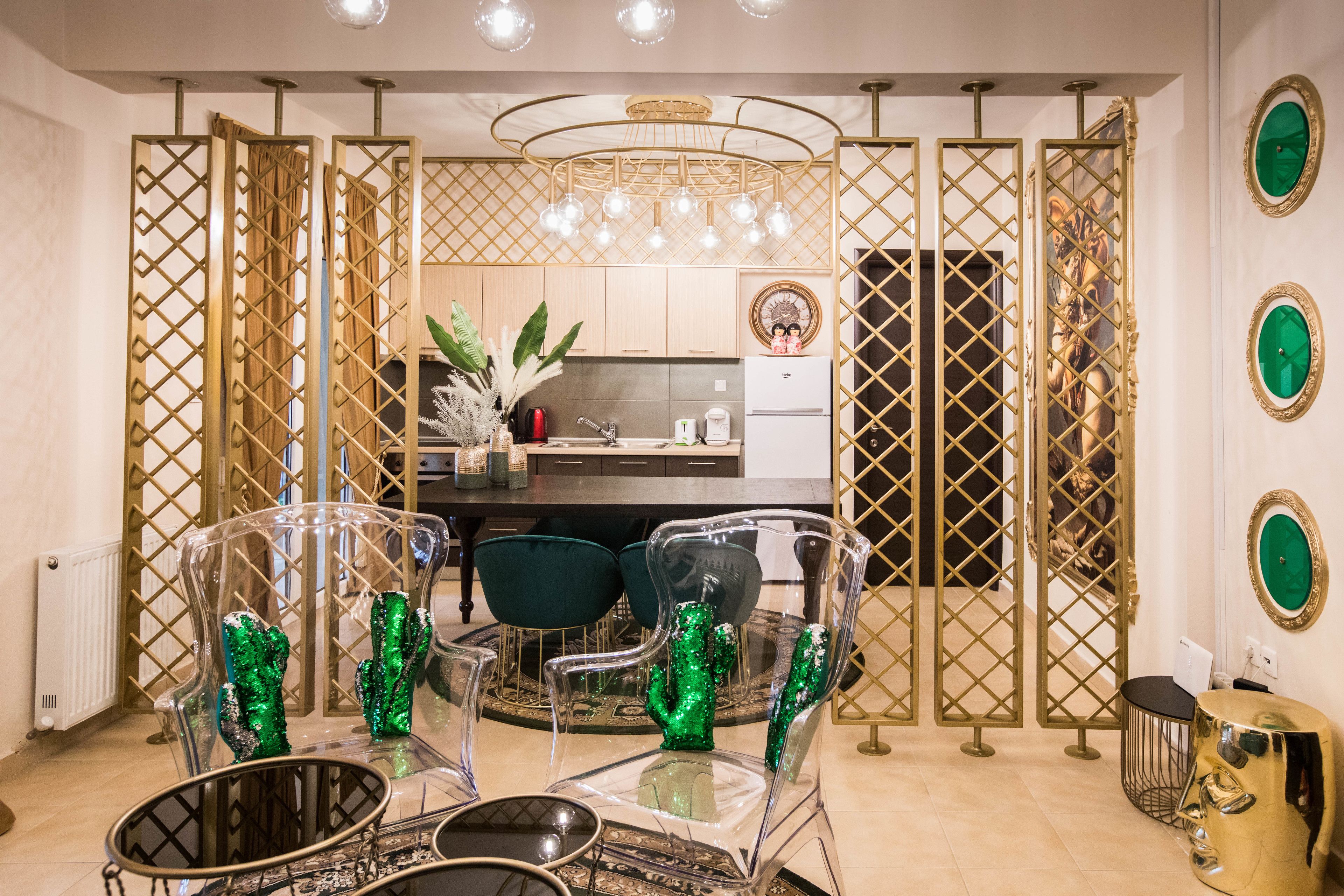 Un comedor moderno con una mesa de vidrio transparente, decoraciones de cactus verdes y una cocina al fondo.